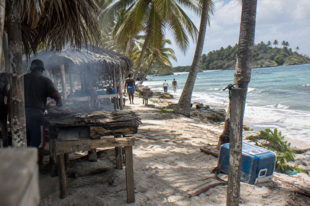 White sand beach with palm trees and simple food stalls along the shoreline