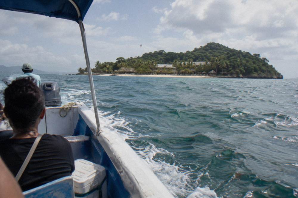 An open passenger boat crossing open water toward a small green island