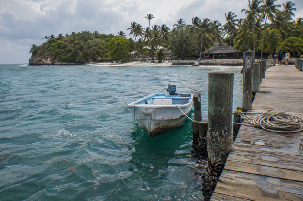 Wooden dock extending into clear shallow water with a small boat moored at the end