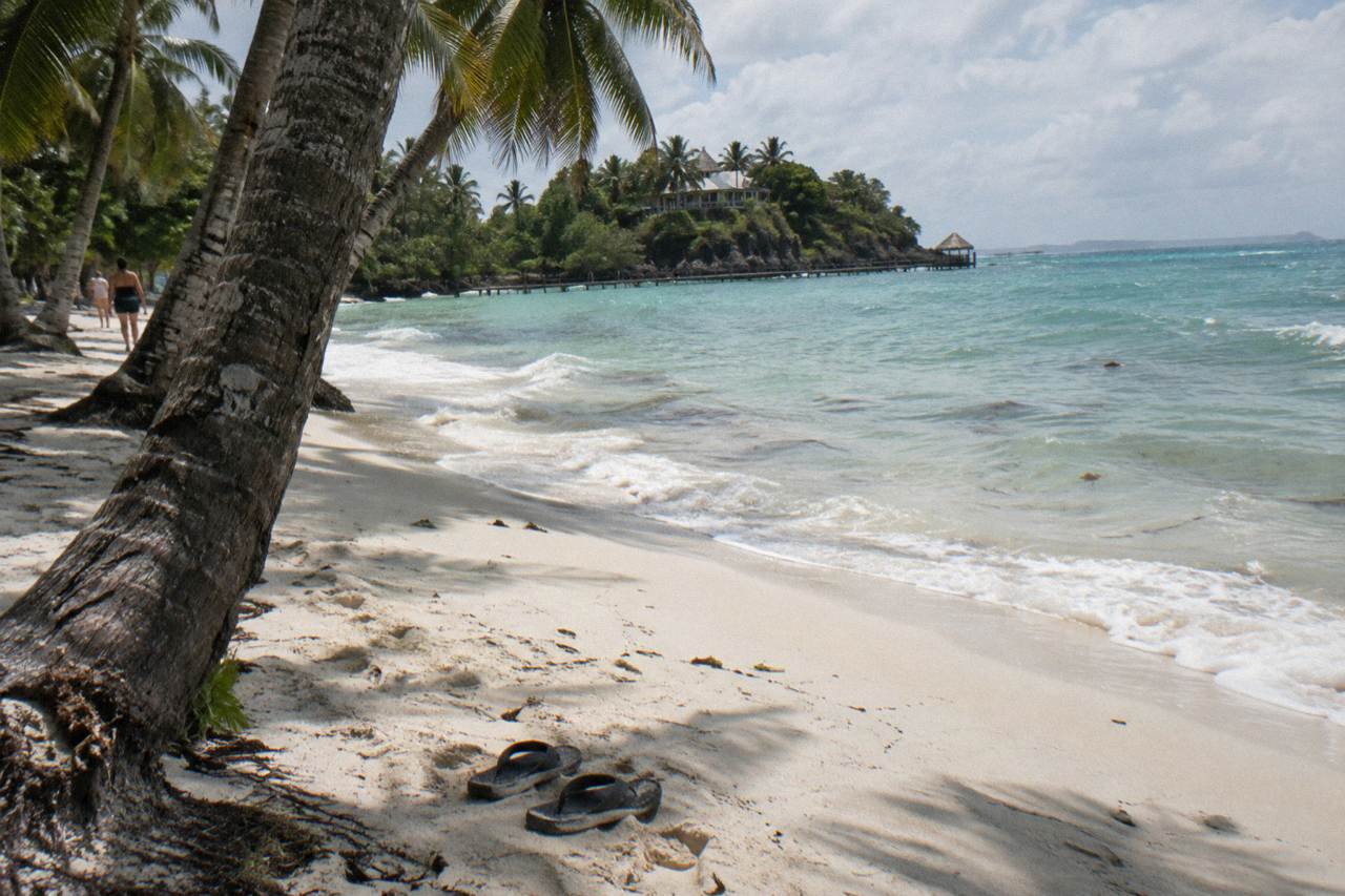 Palm trees leaning over white sand and calm turquoise water at a small Caribbean island beach