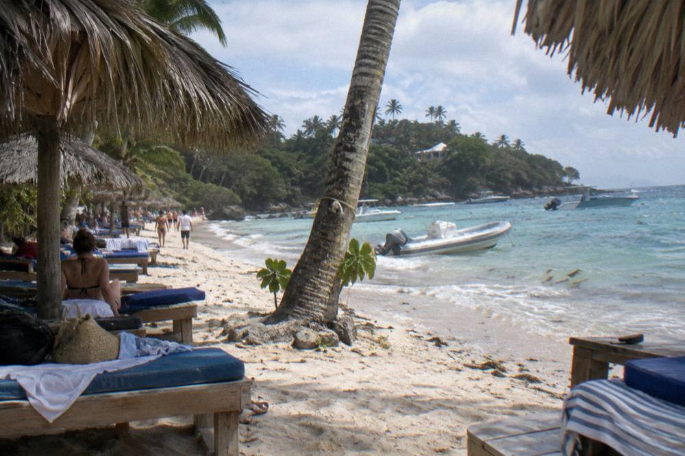 Wooden day beds and thatched umbrellas along a narrow island beach
