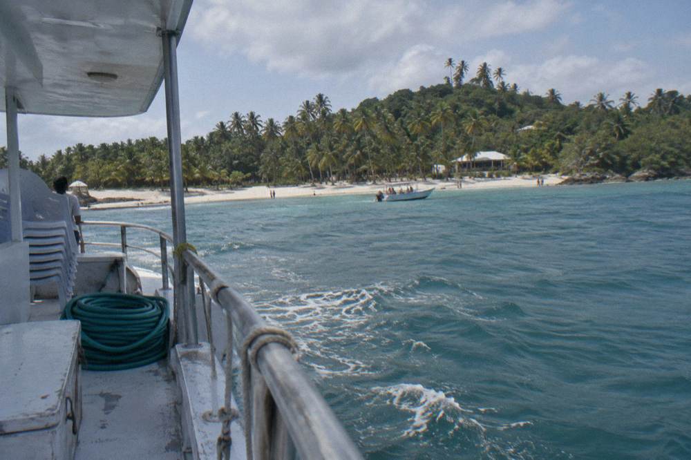 A tour boat anchored offshore of a green island in a calm bay