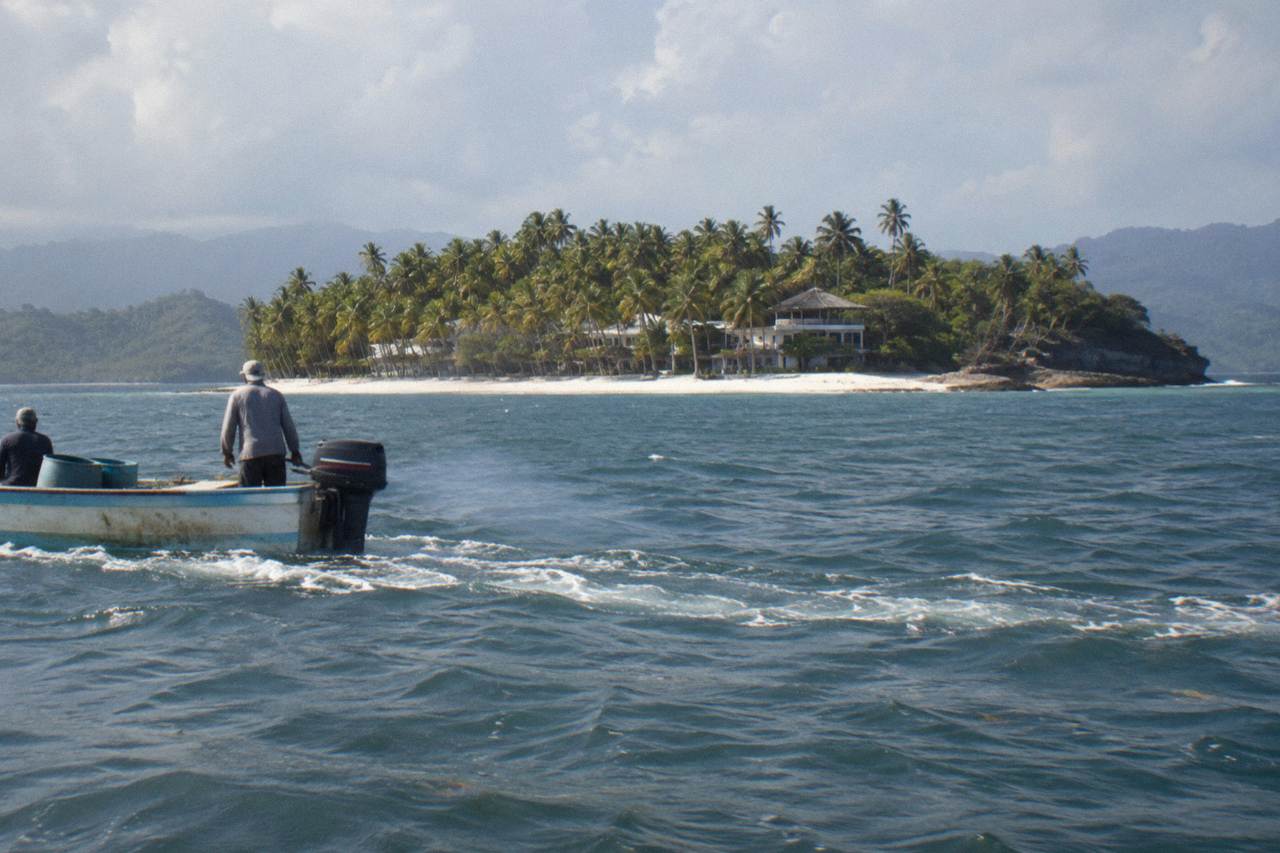 A small palm covered island with white sand and calm turquoise water in Samana Bay