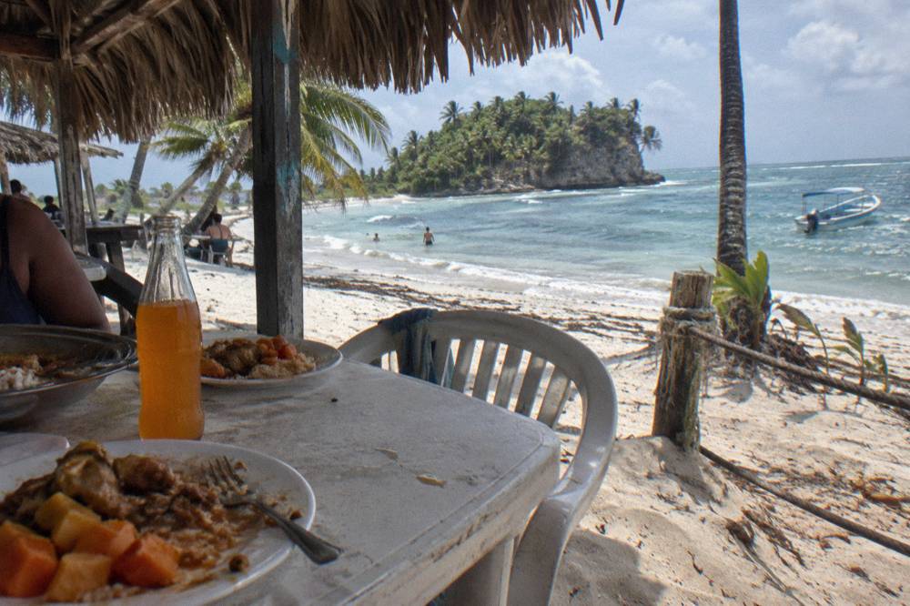A buffet lunch of rice chicken salad and tropical fruit served at a beachside table