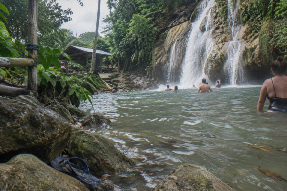 Travelers swimming in the cold natural pool at the base of the waterfall