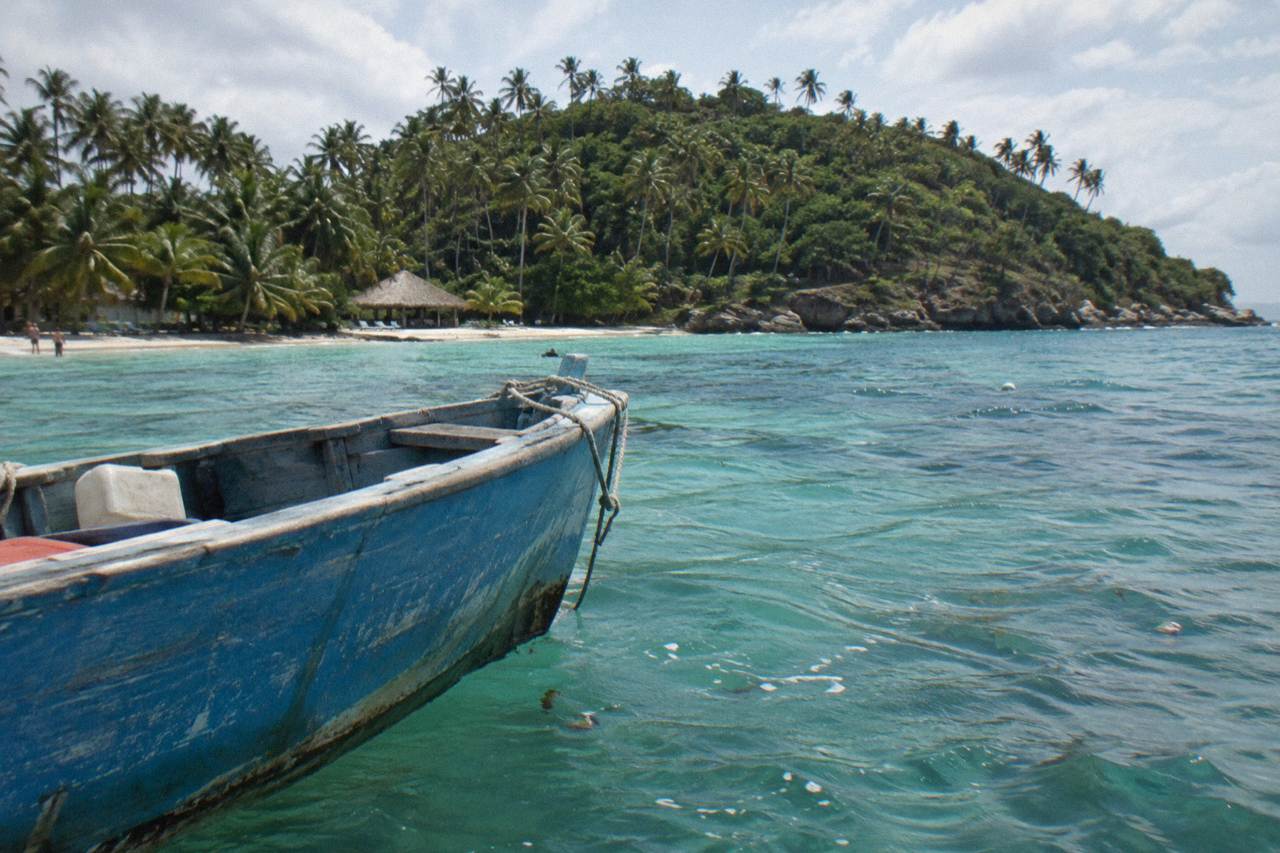 Wooden boat anchored off a small palm covered island in a calm turquoise bay