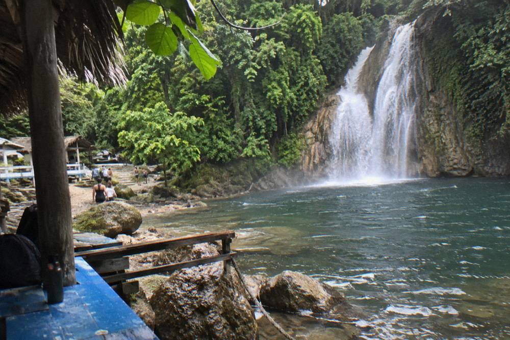 A waterfall dropping through dense tropical forest into a natural pool