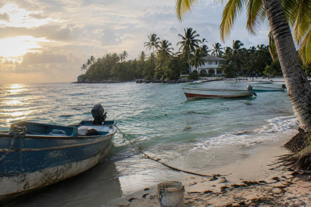 Wooden fishing boats moored in calm turquoise water below palm trees on a Samana beach