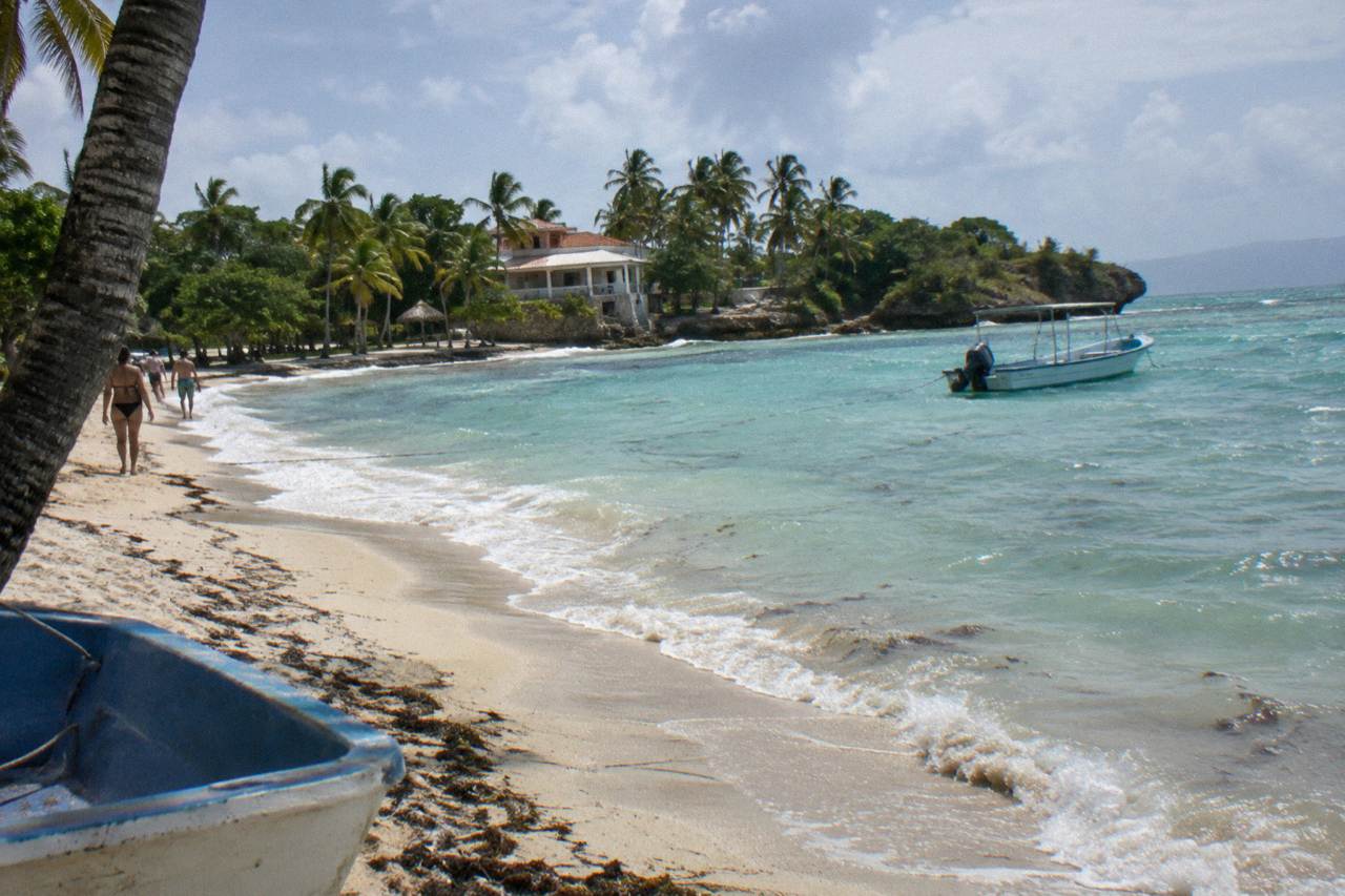 Turquoise shallow water and palm trees along a small island beach in Samana Bay