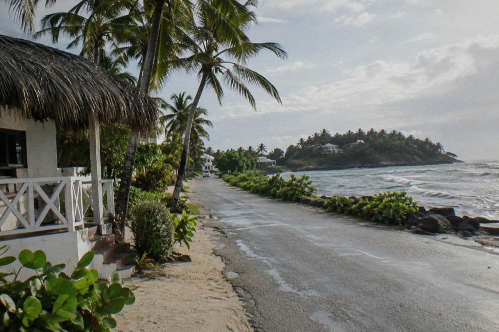 A tour bus parked beside a coastal road overlooking a wide bay in the early morning