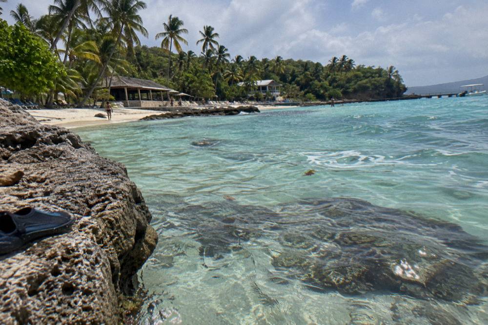 Clear shallow turquoise water over pale sand with darker reef patches visible below the surface