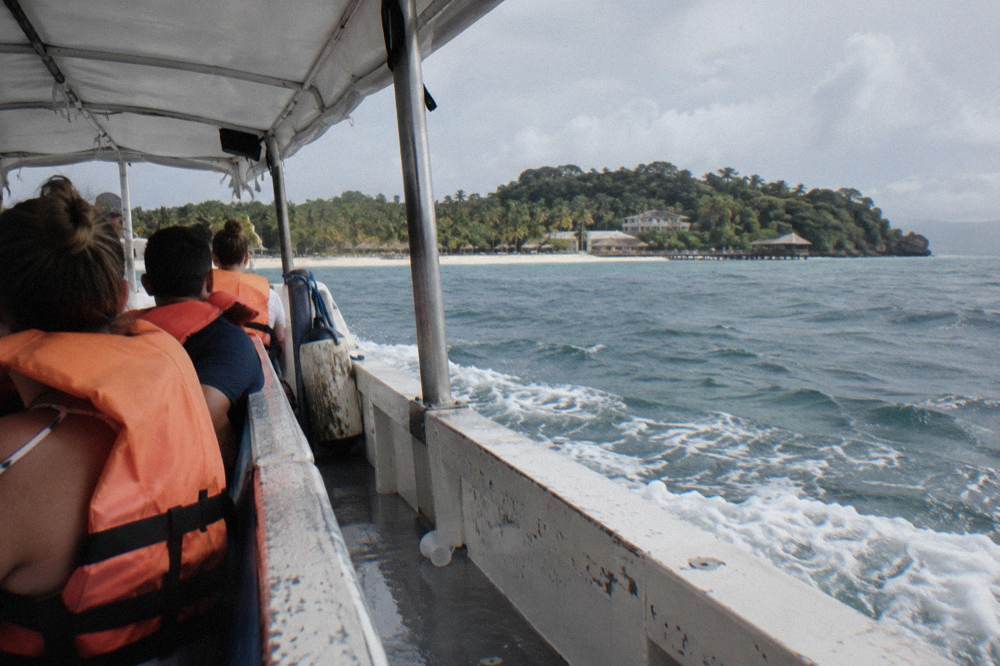 Passengers in life vests seated on a bench aboard a covered boat on blue water