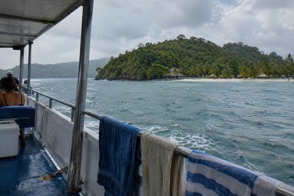 Tour boat on blue water in Samana Bay with green hills of the peninsula in the background
