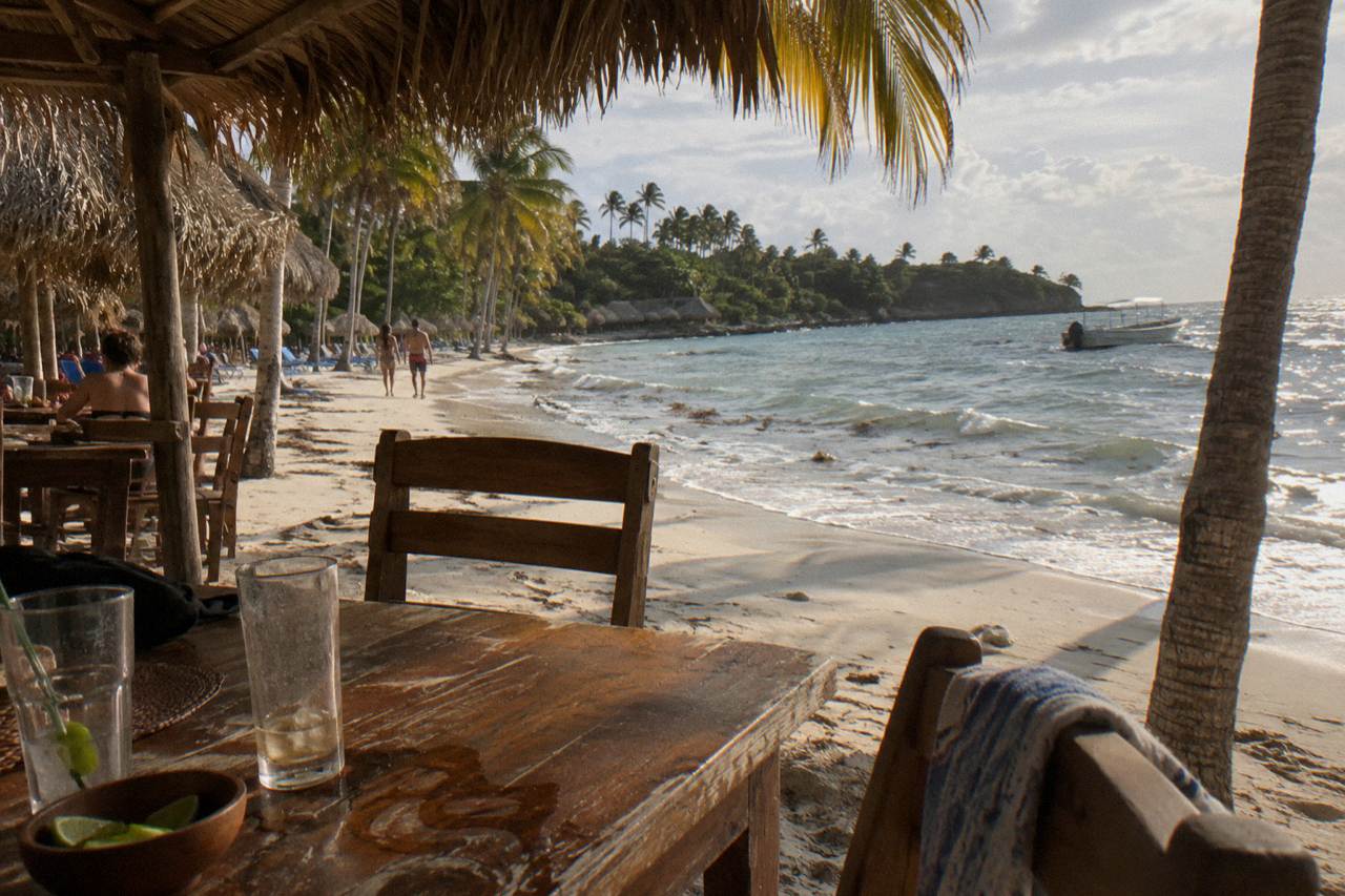Shaded beach restaurant tables beside palm trees on a small tropical island beach