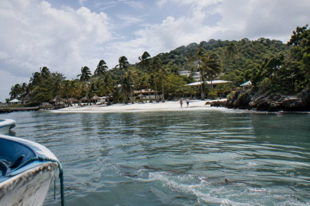 A white sand beach with calm shallow water and a wooded island across the bay