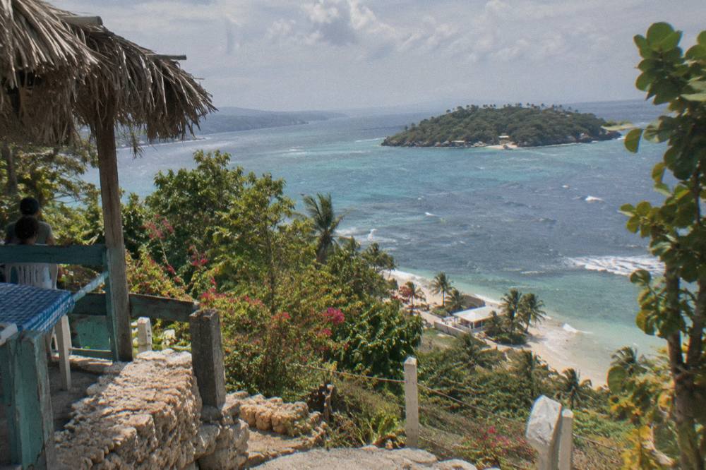 A coastal highway curve with green hills above the water near Samana