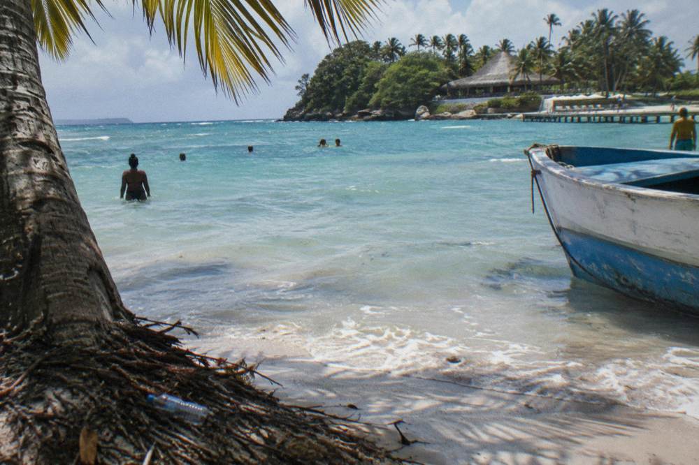 A white sand beach with calm shallow water and palm shade on a small bay island