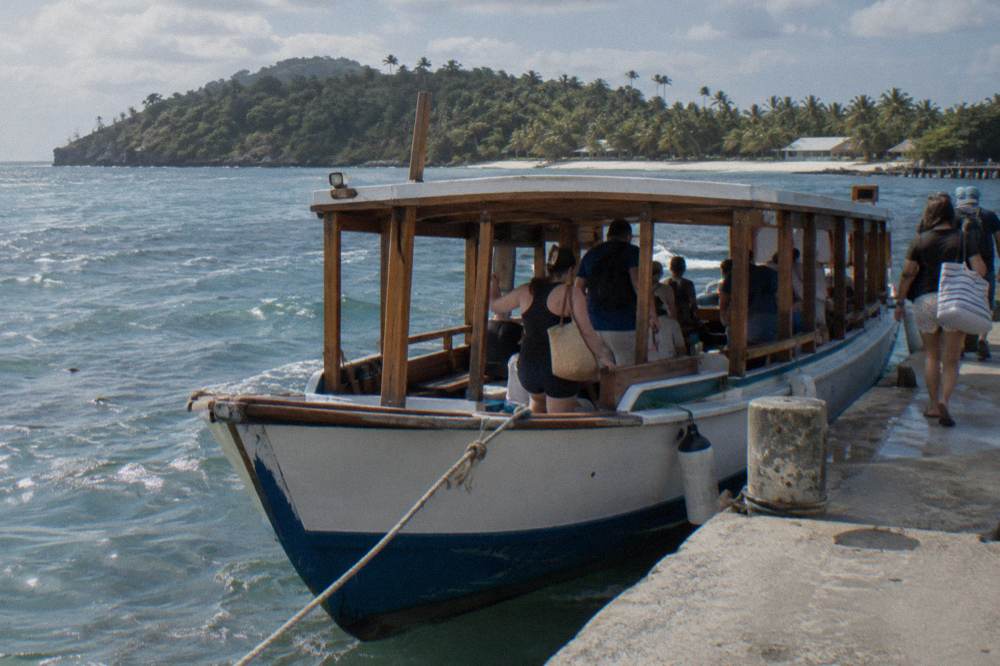 Wooden tour boat moored at a small Caribbean dock with passengers boarding