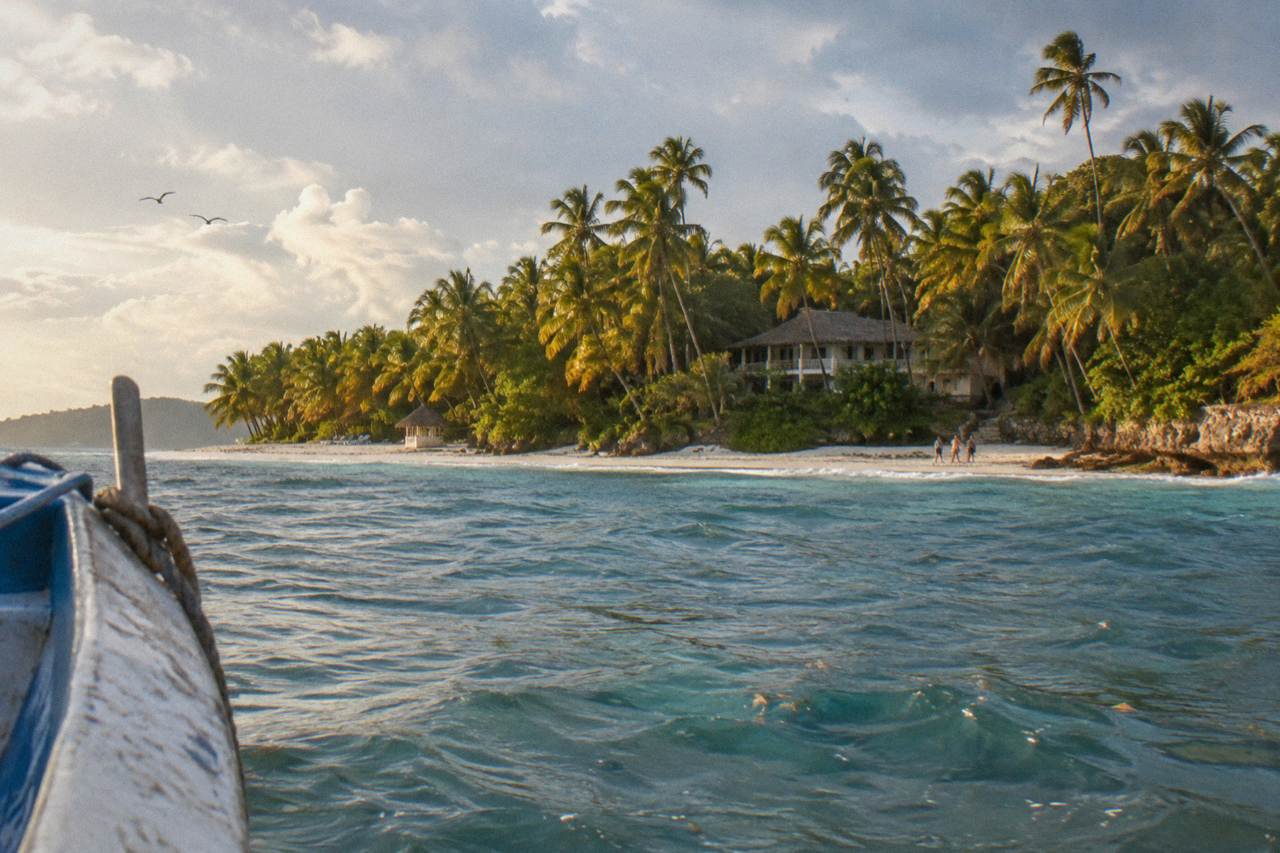Palm-fringed white sand beach on a small island in a calm turquoise bay