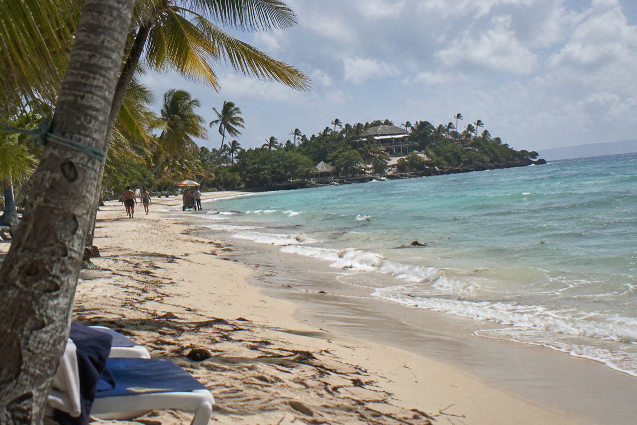 Turquoise water and palm trees along a white sand beach on a small island in Samana Bay