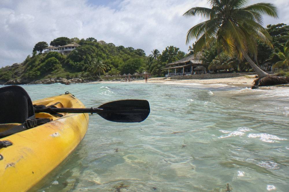 A kayak floating over pale shallow water with an island shoreline in the distance