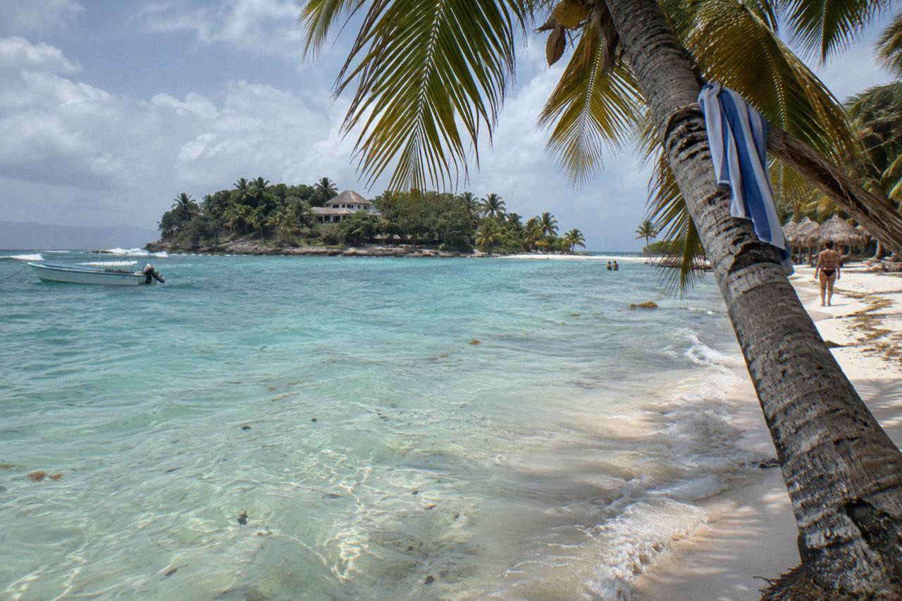 Clear turquoise shallows off a palm-fringed beach on a small island in Samana Bay