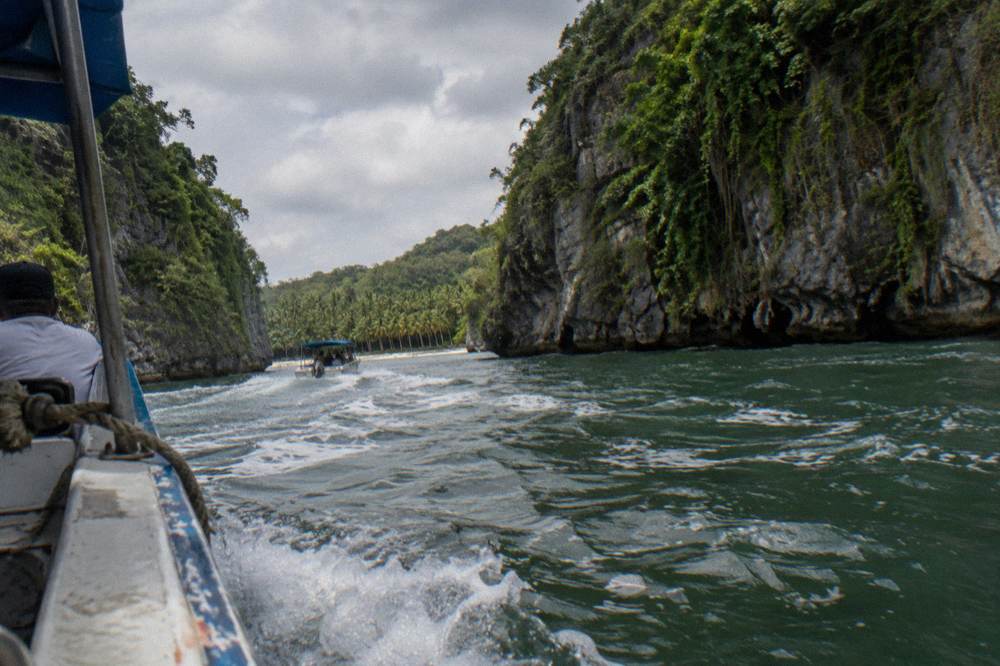Speedboat cruising between tall forested limestone cliffs in a mangrove bay