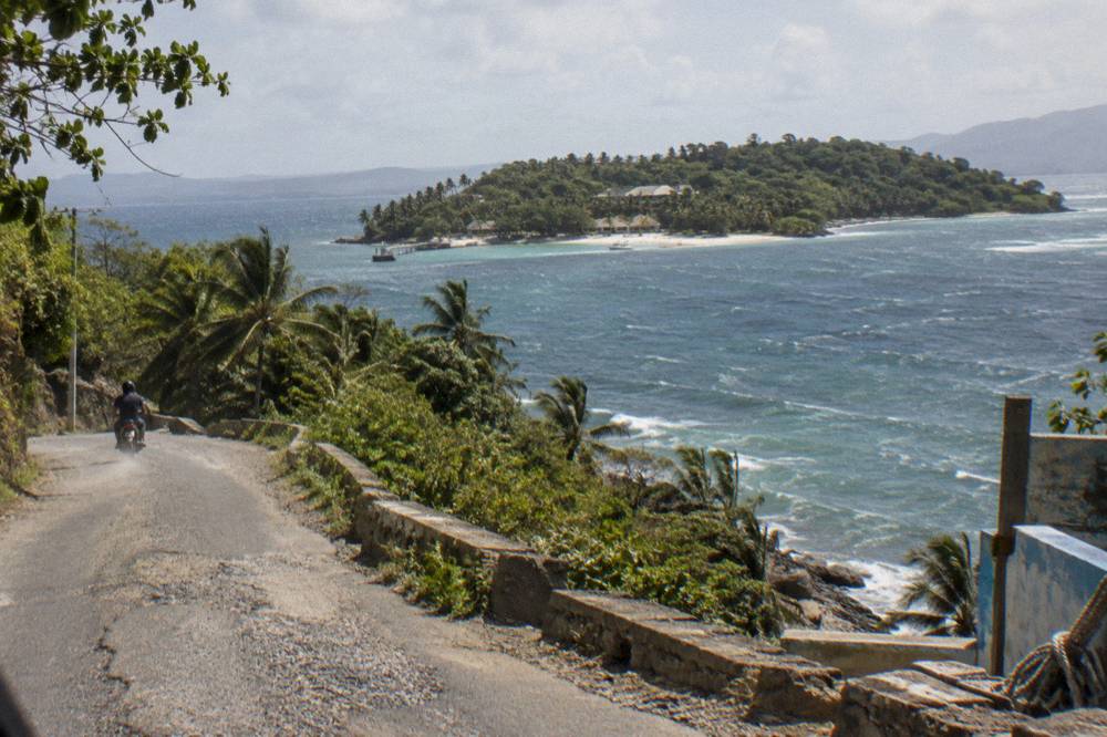 Coastal road winding along a green peninsula above a calm bay