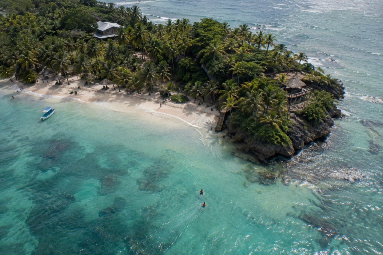 Turquoise water and palm trees along a small island beach in Samana Bay
