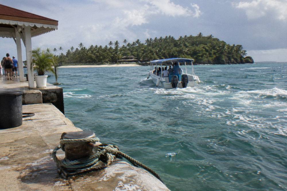 Tour boat approaching a small green island across calm bay water