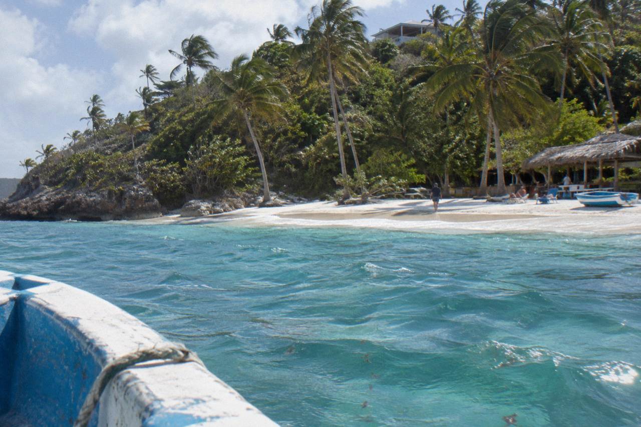 Palm lined white sand beach on a small island in Samana Bay with turquoise water