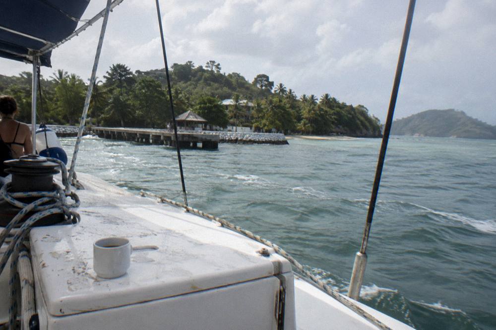 Open deck of a catamaran crossing Samana Bay toward a green island on the horizon