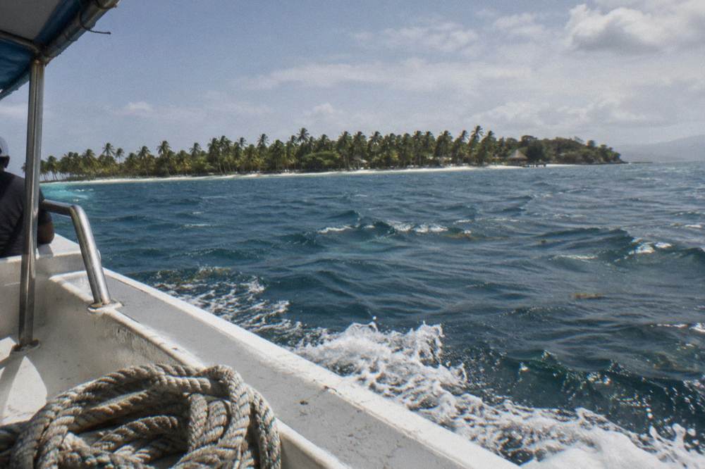 Turquoise bay water with a small wooded island on the horizon