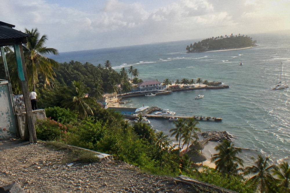 Coastal road curving along a green peninsula toward a small bay town