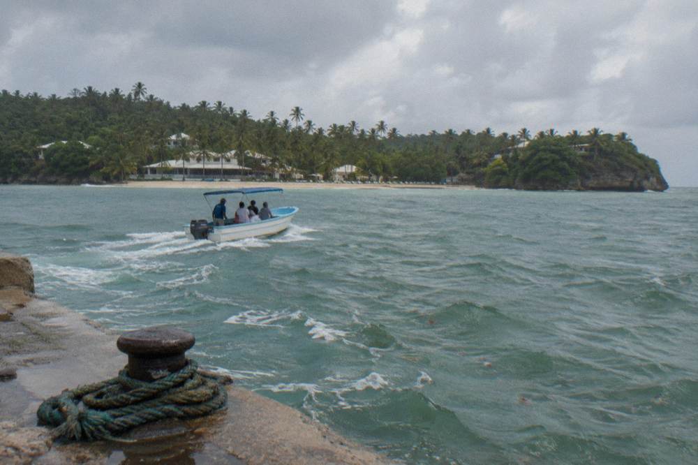Small open boat crossing calm turquoise bay water toward a palm covered island