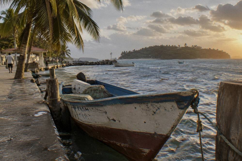 Wooden fishing boat moored beside a waterfront promenade in the late afternoon