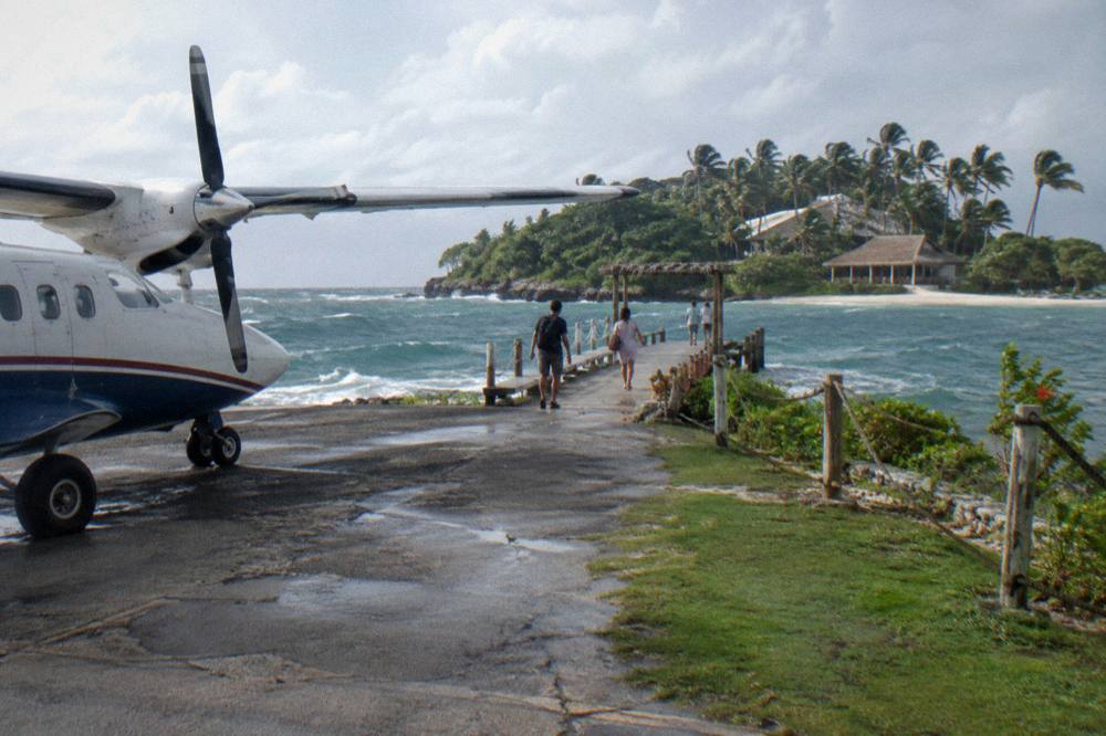 Aircraft parked at a quiet tropical airport apron with palm trees in the background