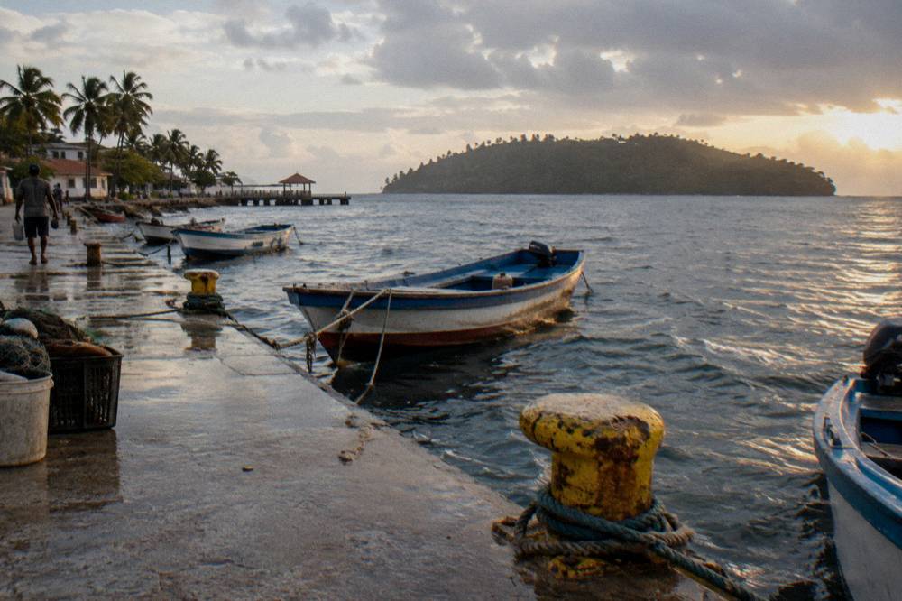 Sunrise over a calm bay with fishing boats near a wooden pier