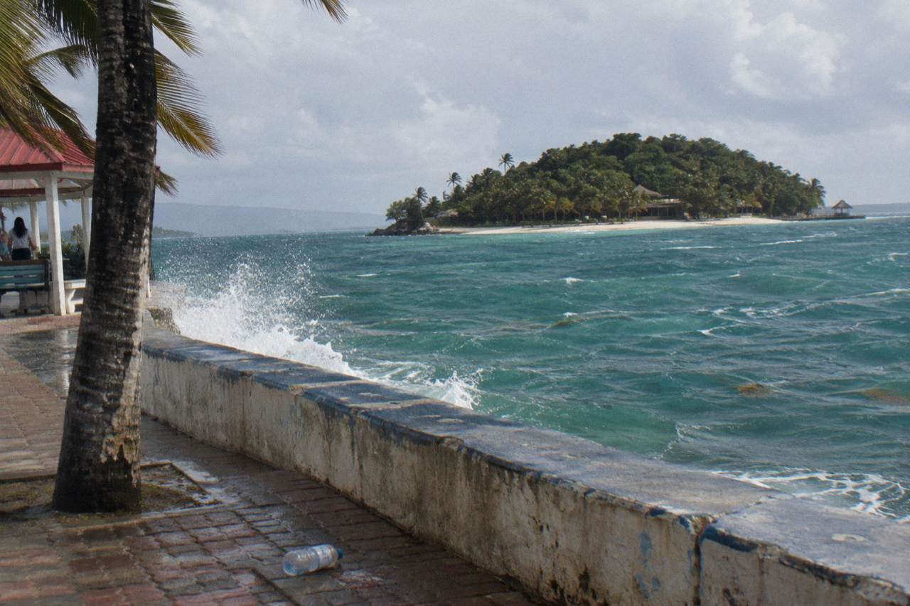 Calm turquoise water of a tropical bay with a small forested island on the horizon