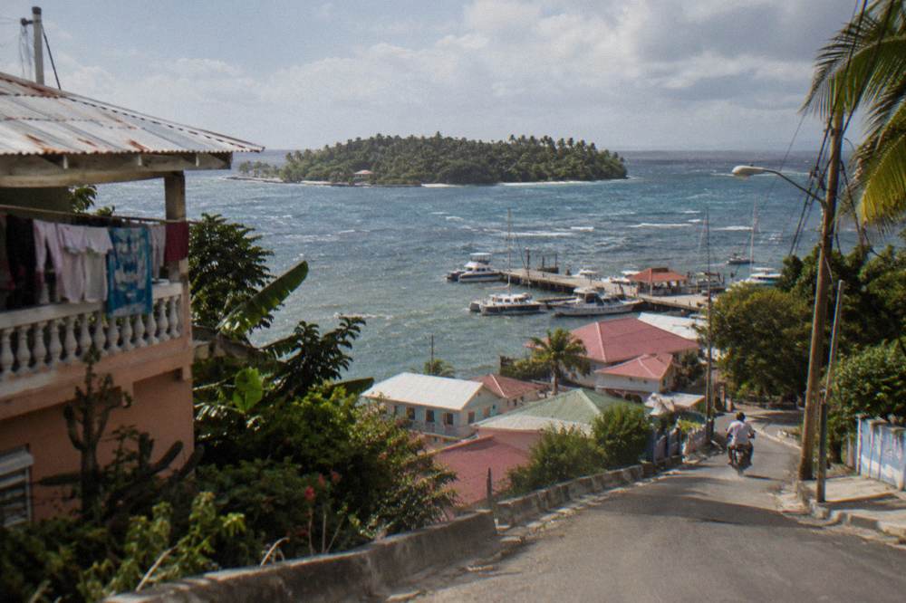 Coastal road winding along green hills toward a bay town