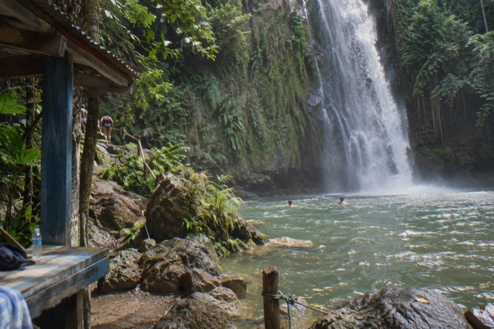 Tall jungle waterfall pouring into a rocky pool surrounded by green forest