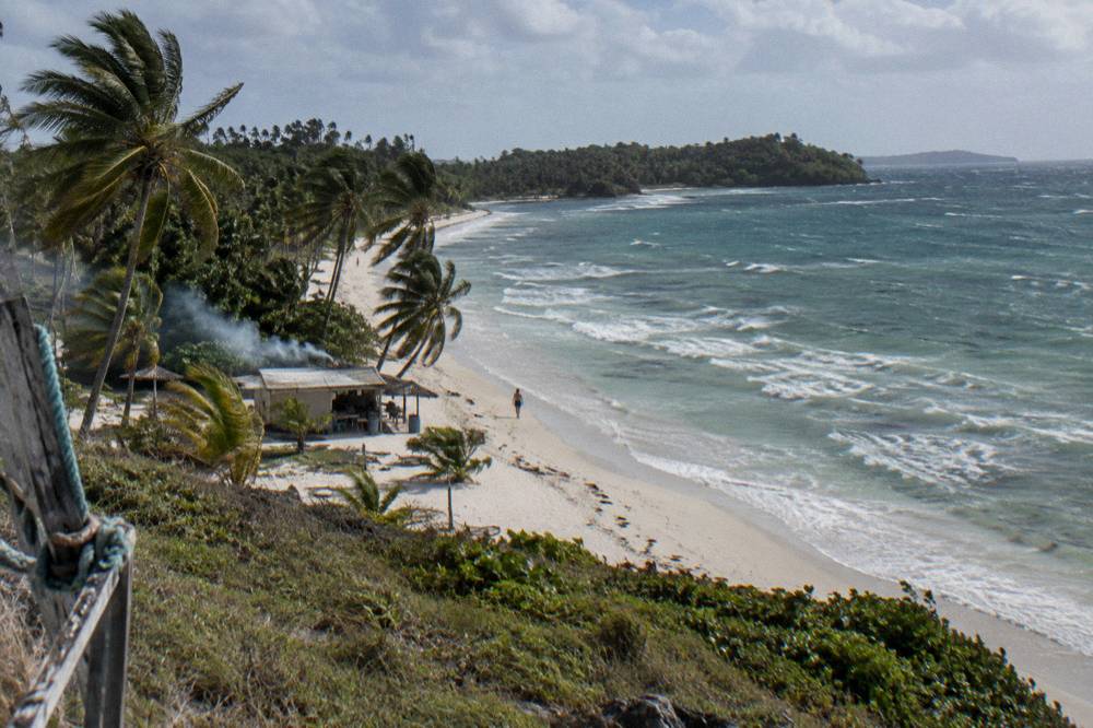Long empty white sand beach with palm trees and clear shallow water at Playa Rincon