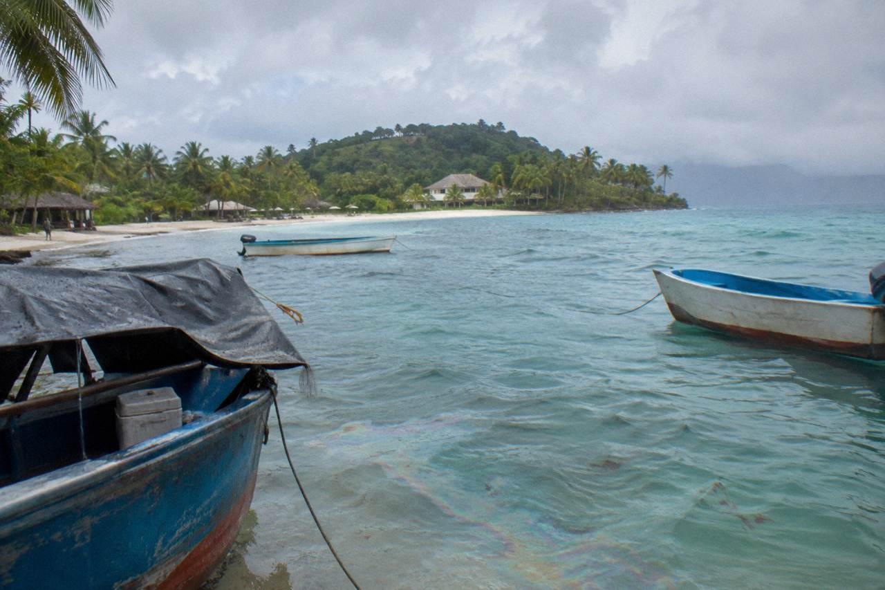 Wooden fishing boats resting on calm turquoise water in Samana Bay with green hills behind
