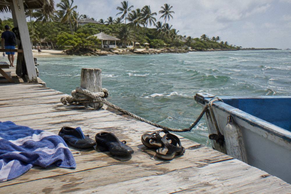Water shoes and sandals drying on a wooden dock beside a moored small boat