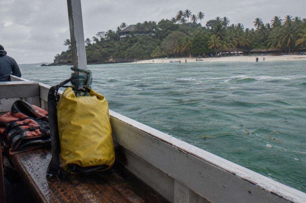 A roll top dry bag closed and resting on the bench seat of a small boat