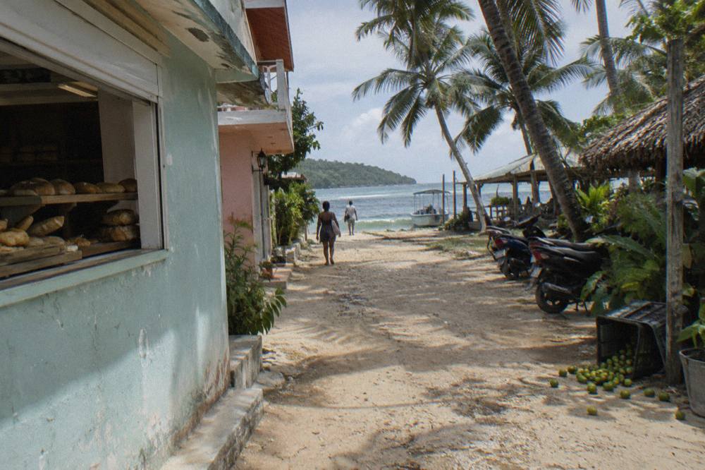A small bay town waterfront with fishing boats moored along a seawall at morning